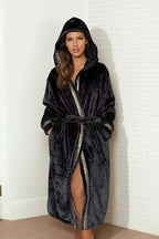 Woman wearing a black hooded Royalty Robe with gold Greek key trim and pockets. Soft bathrobe with hood for women.