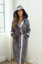 Woman wearing the grey hooded Royalty Robe with gold and silver Greek key trim. Women's soft gray bathrobe with hood and pockets.