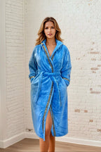 Sky Blue Hooded Royalty Robe - Royalty Robes - Model wearing a long women's bathrobe with hood and gold Greek key trim and pockets. Soft luxury robe for women.