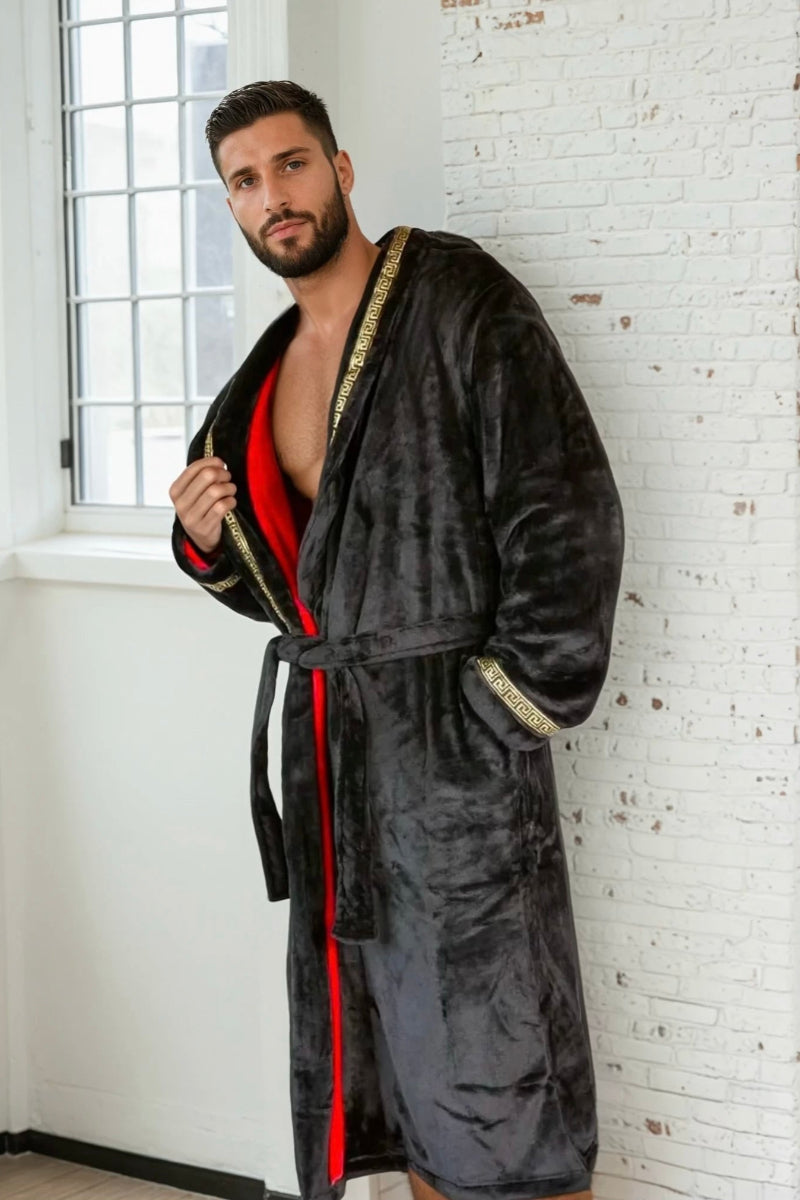 A male model wearing a black robe with red interior and gold Greek key trim. Soft fleece mens bathrobe, housecoat for men.